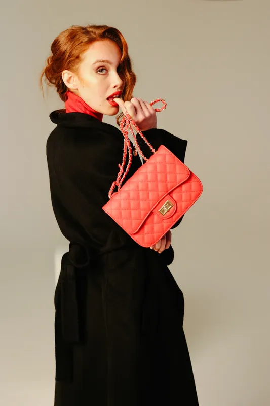 Modella con cappotto nero e borsa trapuntata rossa