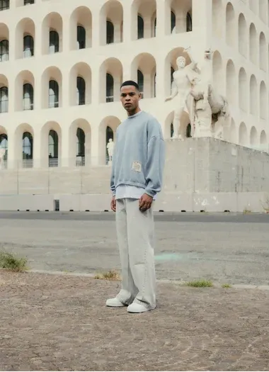 Ragazzo con maglione azzurro davanti al Palazzo della Civiltà Italiana all’EUR di Roma