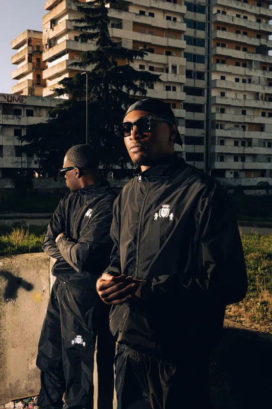 Due ragazzi in tuta nera davanti alle Vele di Scampia